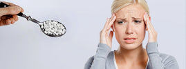 Woman with a headache beside a spoonful of artificial sweetener tablets, possible side effects – SANUSq Health