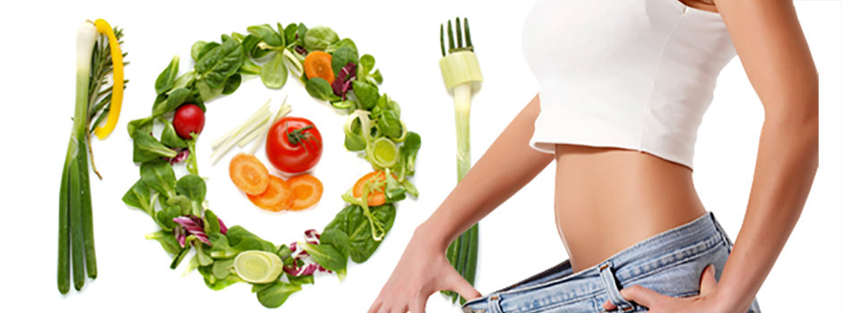 Woman in loose jeans showing weight loss beside a plate of fresh vegetables, jiaogulan for slimming – SANUSq Health