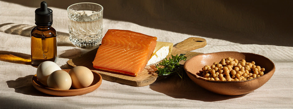 Foods rich in vitamin D3 and K2 — natto, gouda, egg yolk and salmon — in low autumn light